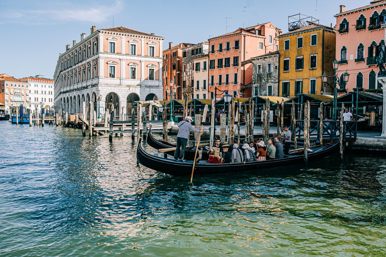 A gondola with passengers cruising through Venice's picturesque canals against historic architecture.